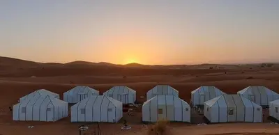 a group of white domes in the desert at sunset at Merzouga Luxury Tent in Merzouga