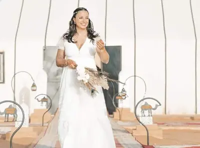 a woman in a white wedding dress holding a bouquet at Merzouga Luxury Tent in Merzouga