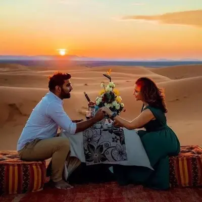 a man and a woman sitting at a table in the desert at Merzouga Luxury Tent in Merzouga