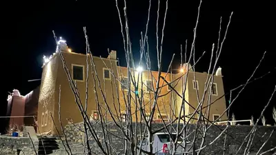 a building with lights in the background at night at Kasbah Citoyenne in Agoudal