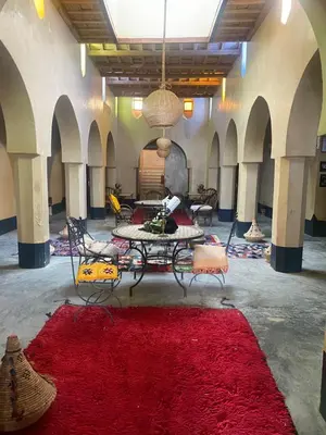 a room with a table and chairs and a red rug at Kasbah Citoyenne in Agoudal