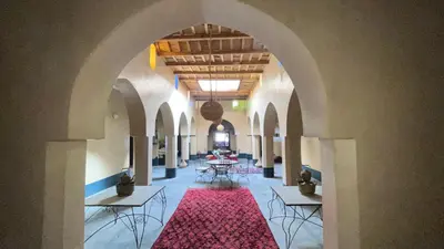 a hallway with tables and chairs and a red rug at Kasbah Citoyenne in Agoudal