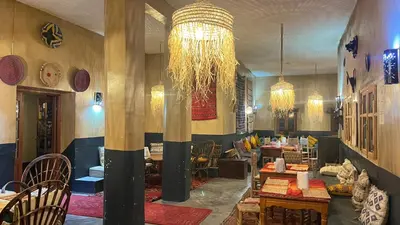 a restaurant with tables and chairs and a chandelier at Kasbah Citoyenne in Agoudal