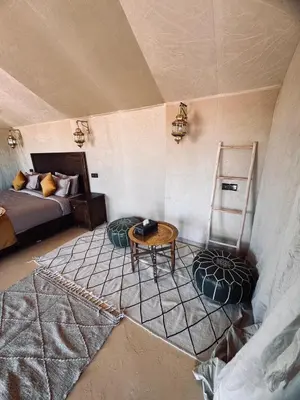 a room with a bed and a table and chairs at Dream Luxury Majestic Camp in Merzouga