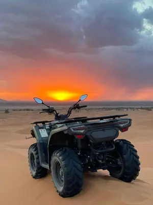 an atv in the desert with the sunset in the background at Dream Luxury Majestic Camp in Merzouga