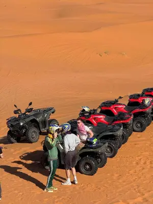 a group of people standing next to a atv in the desert at Dream Luxury Majestic Camp in Merzouga