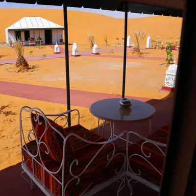 a table and chairs in the middle of the desert at Dream Luxury Majestic Camp in Merzouga