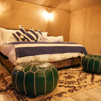 a bedroom with a bed with two ottomans at Dream Luxury Majestic Camp in Merzouga