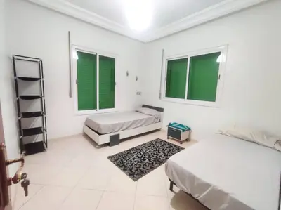 a white room with two beds and two windows at SkyRise Khemisset 2 : 2 bedrooms in Khemisset
