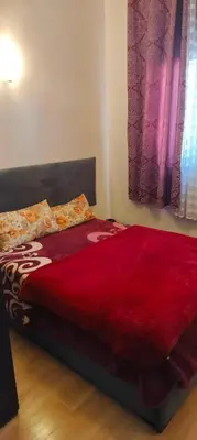 a bed with a red comforter in a bedroom at DAR LAAZIZA in Meknès