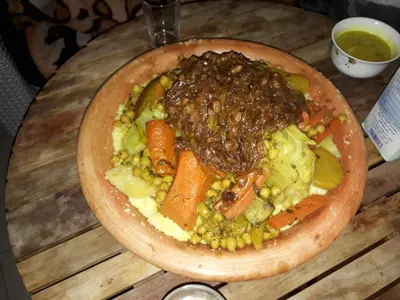 a bowl of food on a wooden table with vegetables at DAR LAAZIZA in Meknès