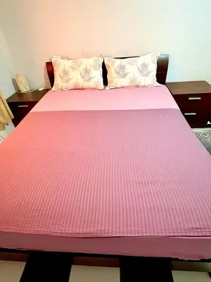 a pink bed with pink sheets and pillows at Spacious Apartment with Motorcycle Garage, Free Parking, and Air Conditioning in Er Rachidia