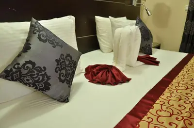 a bed with white boots and pillows on it at Hotel Al Akha in Sidi Harazem