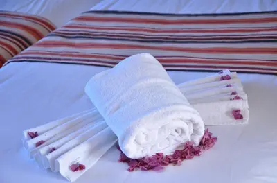 a white towel and chopsticks on a bed at Hotel Al Akha in Sidi Harazem