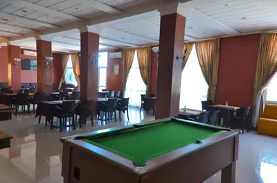 a pool table in a room with tables and chairs at Hotel Al Akha in Sidi Harazem