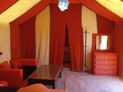 a living room with a tent with a table and a mirror at Africa Magic Camp in Merzouga