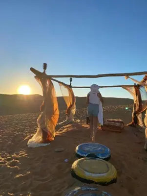 a woman standing on a beach with a group of nets at Africa Magic Camp in Merzouga