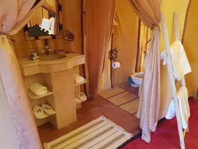 a bathroom with a tent with a toilet and a sink at Africa Magic Camp in Merzouga
