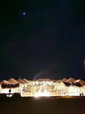a view of a resort at night with the moon at Sahara Luxury Camp in Merzouga