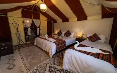 a hotel room with three beds with white sheets at Sahara Luxury Camp in Merzouga