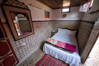 a small bedroom with a bed and a mirror at Dar Chourouk in Fès