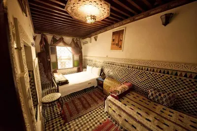 a small bedroom with a bed and a couch at Dar Chourouk in Fès