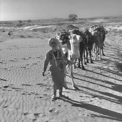 a man walking in front of a herd of cows at Guesthubcamp in Merzouga