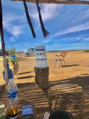 a table with bottles of water and chairs in the desert at Guesthubcamp in Merzouga