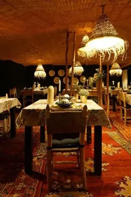 a dining room with a table and chairs in a room at Guesthubcamp in Merzouga