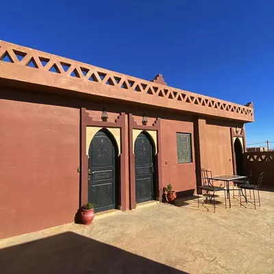 a building with two black doors and a table at Dar Hassi Labied Merzouga in Hassilabied