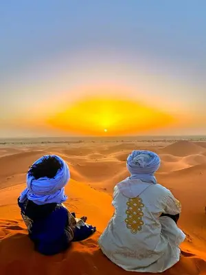 two people sitting in the desert watching the sunset at Dar Hassi Labied Merzouga in Hassilabied