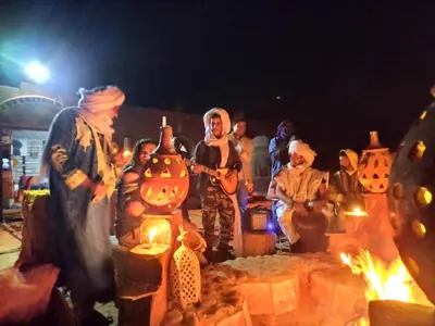a group of people dressed in pumpkin costumes standing next to a fire at Desert Chegaga Luxury Camp in El Gouera