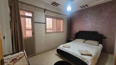 a bedroom with a bed with a black headboard and two windows at Charme & Confort au Cœur de Meknes in Meknès
