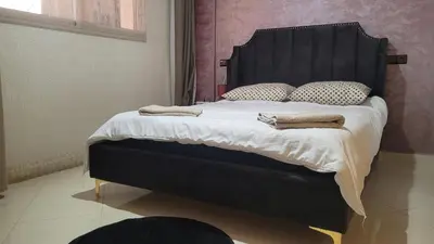 a bed with a black headboard and pillows on it at Charme & Confort au Cœur de Meknes in Meknès