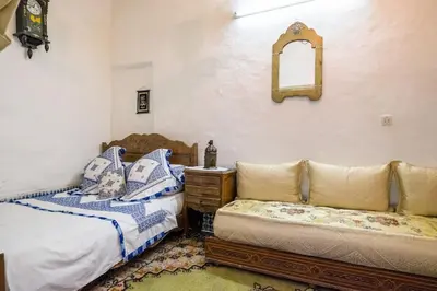 a bedroom with two beds and a couch and a mirror at Dar Fatimazahra in Fès