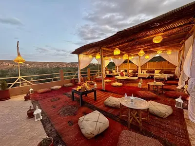 an outdoor living area with tables and couches on a roof at Riad Sahara Stars Dades in Boumalne