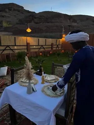 a woman standing at a table with a white table cloth at Riad Sahara Stars Dades in Boumalne