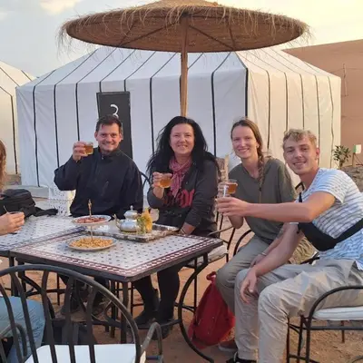 a group of people sitting at a table with drinks at Camel Experience Camp in Merzouga