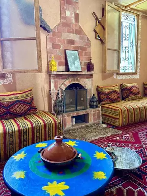 a living room with a table and a fireplace at Villa Mouloud, Authentic Amazigh Family Villa, Fireplace & Garden in Khenifra