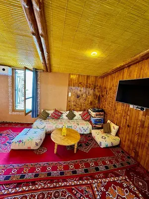 a room with two beds and a table and a tv at Villa Mouloud, Authentic Amazigh Family Villa, Fireplace & Garden in Khenifra