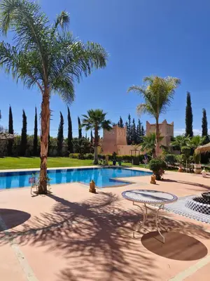 a swimming pool with palm trees and a resort at Les jardins d’ailleurs in Marrakech