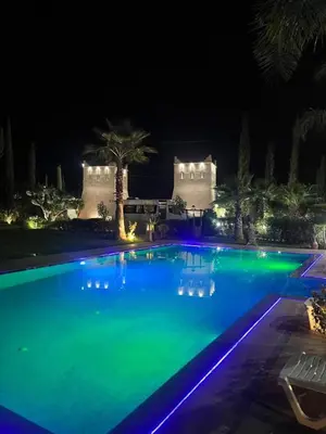 a large swimming pool with blue and green lights at Les jardins d’ailleurs in Marrakech