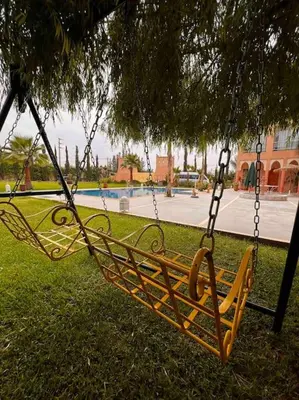 a swing hanging from a tree in a park at Les jardins d’ailleurs in Marrakech