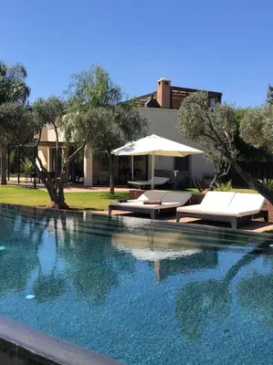a large swimming pool with lounge chairs and an umbrella at Villa privée dans un environnement idyllique in Marrakech