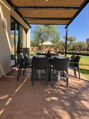 a patio with a table and chairs under a pergola at Villa privée dans un environnement idyllique in Marrakech