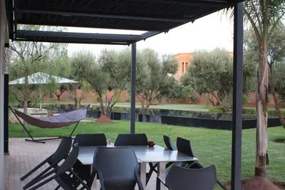 a patio with a table and chairs and a hammock at Villa privée dans un environnement idyllique in Marrakech