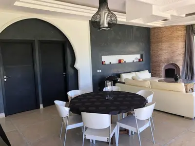 a dining room with a black table and white chairs at Villa privée dans un environnement idyllique in Marrakech