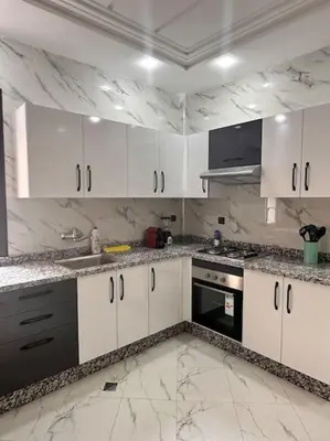 a kitchen with white cabinets and marble counter tops at Family confort Fes in Fès