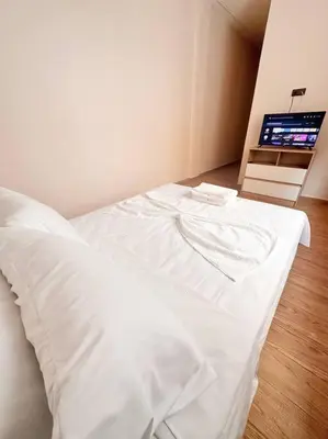 a white bed in a room with a television at Family confort Fes in Fès
