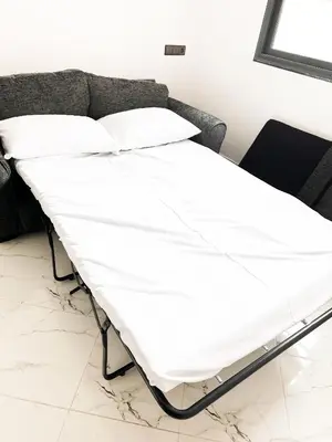 a white bed in a room with a couch at Family confort Fes in Fès